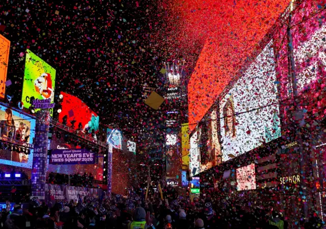Una multitud en Times Square, Nueva York, recibe una lluvia de papeletas coloridas entre los avisos iluminados en los edificios