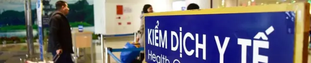 Arriving passengers walk past a health quarantine sign at Noi Bai International Airport in Hanoi on January 21, 2020.