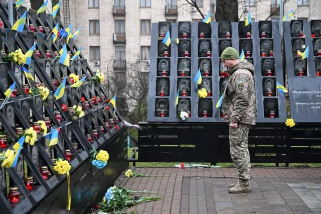 Військовий стоїть біля пам'ятного знака з фотографіями загиблих під час Єіромайдану