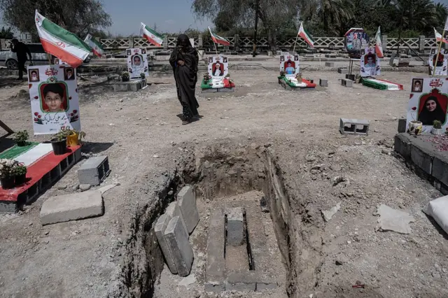 گورستانی که کودکان مدرسه ابتدایی شجره طیبه در میناب در آن دفن شده‌اند؛ تصویر هر کودک در بالای هر قبر نصب شده، زنی سیاه‌پوش در گورستان دیده می‌شود