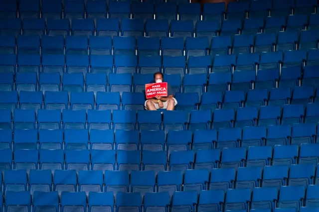 A man holding a sign sits alone