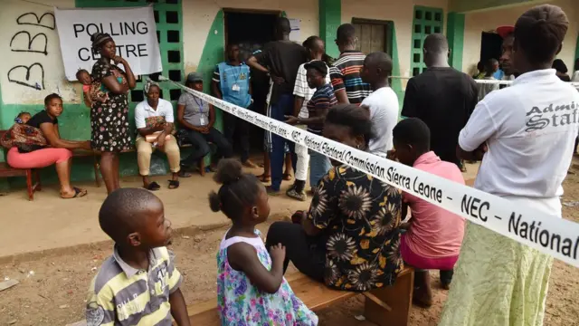 People wait outside a polling station to cast their vote during the country's general elections in Freetown on March 7, 2018. More than 3.1 million voters are registered for the polls across the small West African nation