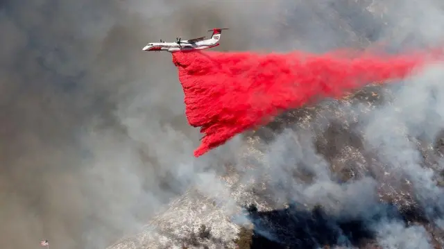 Pesawat menebarkan bubuk saat kebakaran melahap hutan di Mandeville Canyon, Los Angeles, California, AS, 11 Januari 2025.