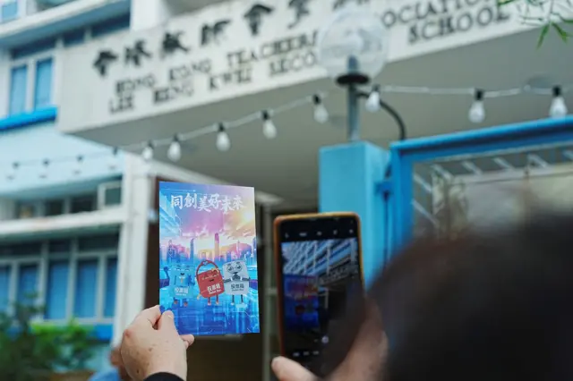 有市民在票站外手持写有“同创美好未来”的心意卡拍照。