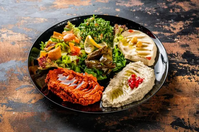 Bir tabakta humus, muhammara, sarma, babaganuş gibi mezeler duruyor..