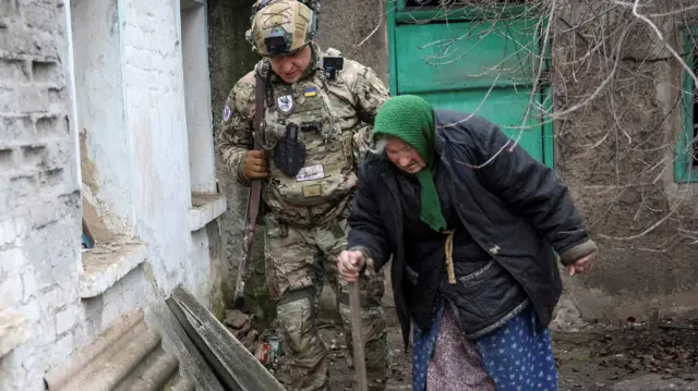 Członek oddziału ewakuacyjnego policji „Białe Anioły” pomaga mieszkańcowi podczas ewakuacji z miasta Dobropole na linii frontu, w trakcie ataku Rosji na Ukrainę, w obwodzie donieckim na Ukrainie, 9 grudnia 2022 r.