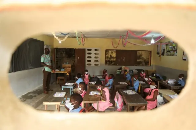 Les élèves, portant des masques de protection, sont photographiés à travers la fenêtre pendant une leçon.