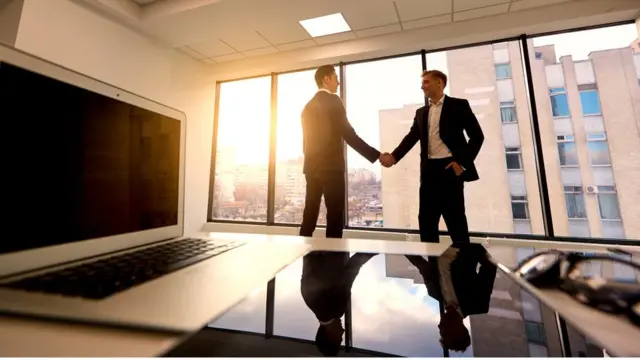 Dos personas dándose la mano en una oficina