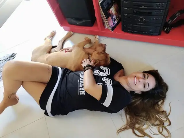 Mulher deitada no chão ao lado de cachorro; ela sorri