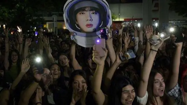 Penggemar boy band K-Pop yang tidak dapat menghadiri pertunjukan, berkumpul di luar stadion Monumental River Plate untuk mendengarkan Kim Seok-jin -alias Jin- menampilkan single solonya "The Astronaut".