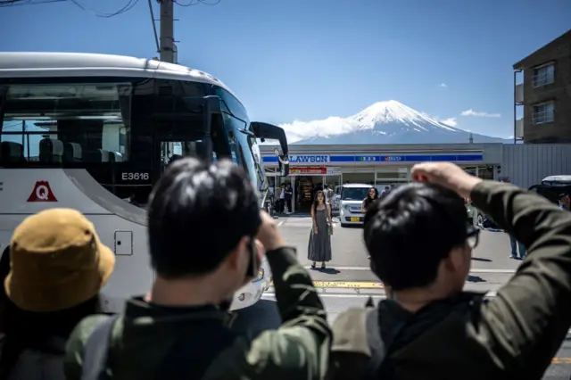 Turistas tirando fotos do outro lado da rua com o Monte Fuji em 3 de maio de 2024