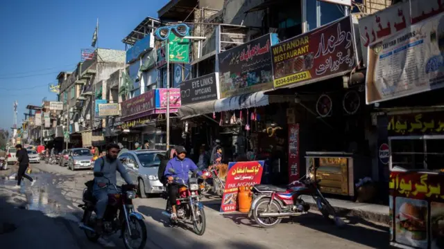 بازار منطقه پشاور مور. دو موترسایکل در حال عبور از بازار هستند