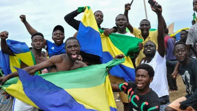 Abantu muri Gabon bazunguza amabendera y’igihugu mu kwishimira ko igisirikare cyahiritse ubutegetsi, aha ni mu mihanda y’i Akanda, muri Gabon, ku itariki ya 30 Kanama (8) mu 2023 