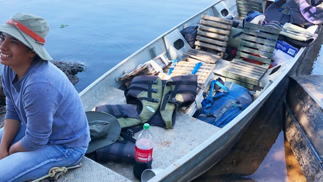 Maira Martinez durante un viaje de campo en un bote que contiene carpetas con plantas prensadas