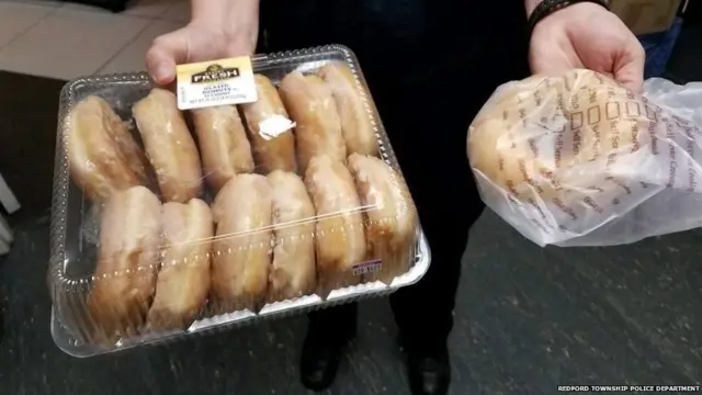 Police officer holding donuts and a bagel