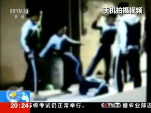 被打倒的孩子倦伏在地，受到反复踢打