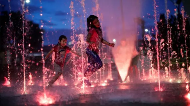 Niñas juegan en una fuente en Tapachula, México.