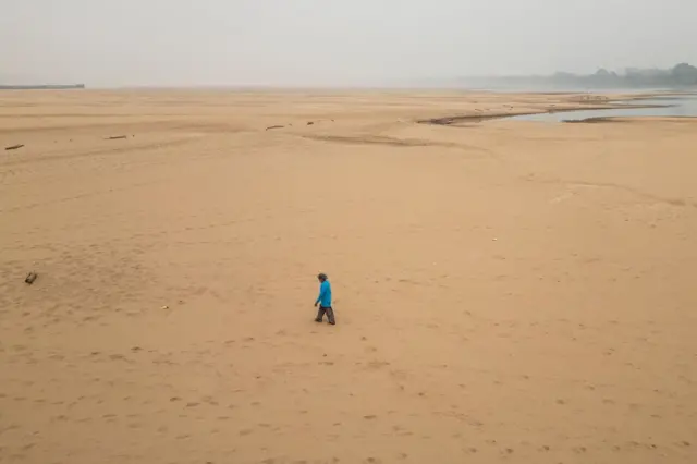 Fotografia aérea mostrando um homem caminhando em um banco de areia formado pelo nível histórico baixo do Rio Madeira