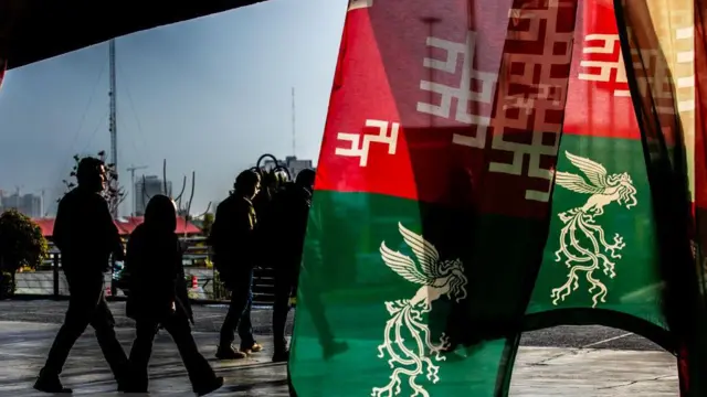 چند نفر از یکی از سینماهای جشنواره فیلم فجر خارج می‌شوند. پرچم‌هایی با لوگوی جشنواره در پس‌زمینه دیده می‌شود.