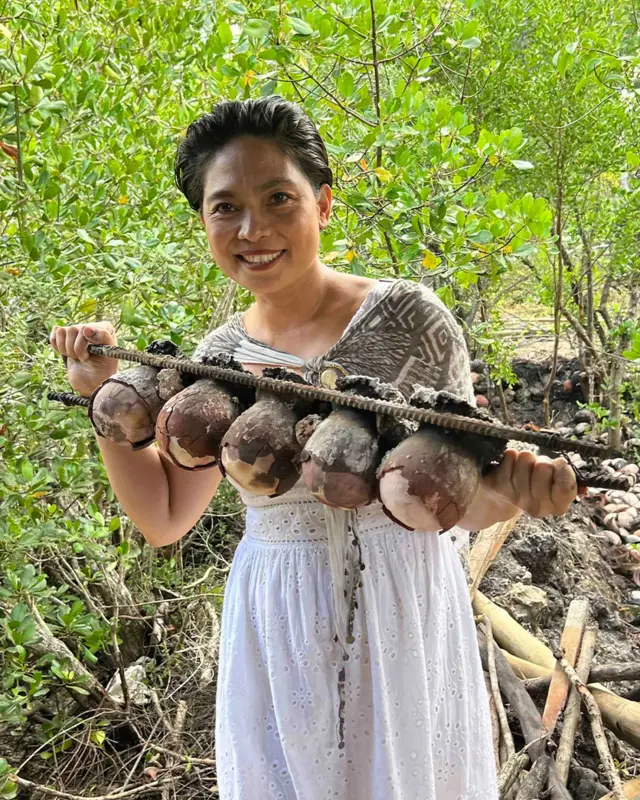 Жінка тримає кілька "яєць" солі, закріплених між двома металевими жердинами