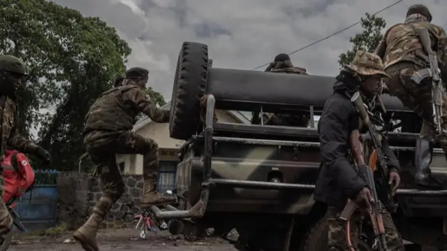 Des soldats des Forces armées de la RDC montent sur une voiture de patrouille sur la route nationale 2 en bordure de la zone qui a été attaquée par les rebelles du M23