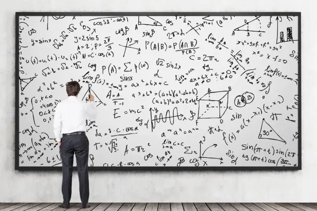 Un hombre escribiendo fórmulas en un pizarrón.