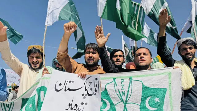 Yeşil renkli pankartlar ve bayraklar taşıyan, tezahürat yapan ve el sallayan bir grup insan.