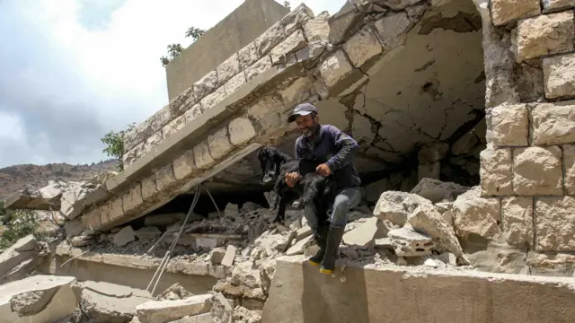 A man clambers over a collapsed building