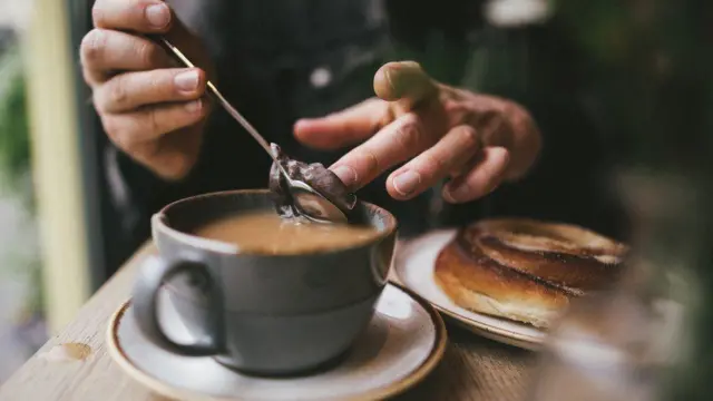 A tea drinker removes the tea bag from their cup
