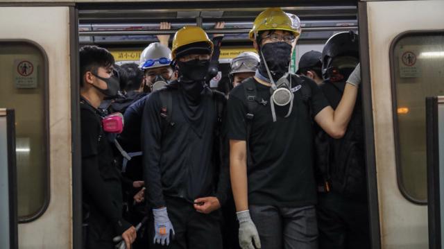 香港九龙港铁九龙湾站一群蒙面示威者搭乘港铁列车离开（台湾中央社图片10/8/2019）