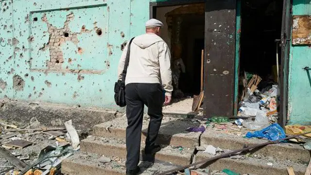 Чоловік заходить у зруйнований під'їзд будинку на Донеччині. Чоловік заходить у зруйнований під'їзд будинку на Донеччині.