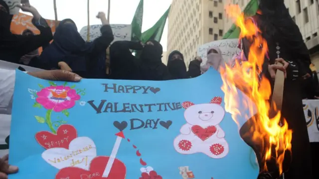 Pakistani women wey dey di Jamiat-e-Ulama Pakistan religious party dey burn Valentine card for di protest wey dem do for Karachi for 14 February 2012