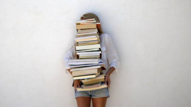 chica sosteniendo pila de libros