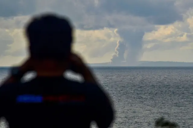 Seorang pria mengamati gunung berapi Anak Krakatau saat menyemburkan abu ke udara selama letusan di Selat Sunda 4 Februari 2022. 