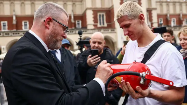 Grzegorz Braun, członek skrajnie prawicowej partii Konfederacja, składa autograf na gaśnicy podczas wiecu wyborczego do Parlamentu Europejskiego w Krakowie, 4 czerwca 2024 r.