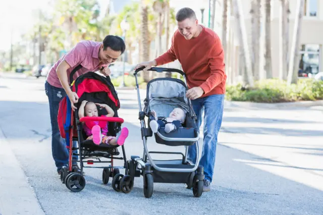 Dos padres jóvenes viendo a sus bebés en sus coches.
