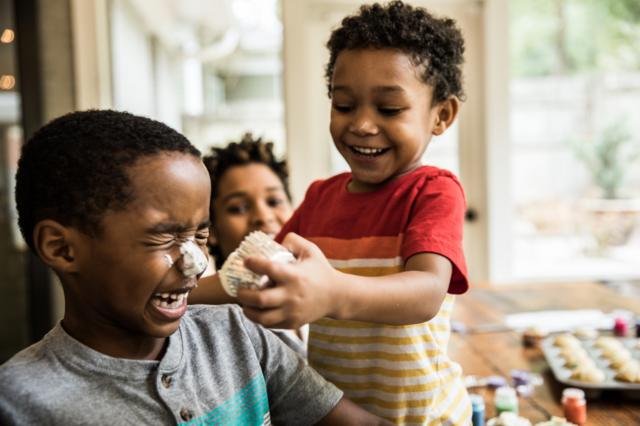 Criança negra passa um bolinho no rostocasino 440 casinooutra criança negra; ambas riem