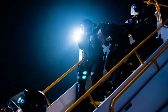 Un deportado procedente de Estados Unidos baja custodiado del avión en El Salvador, el 16 de marzo de 2025. (Foto: cortesía del gobierno de El Salvador vía Getty Images).