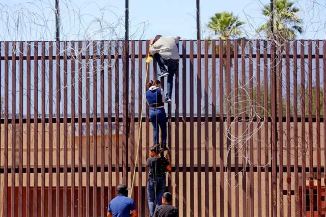 Người di cư đang cố trèo qua bức tường biên giới Mỹ-Mexico. Ảnh chụp vào tháng 5/2023 