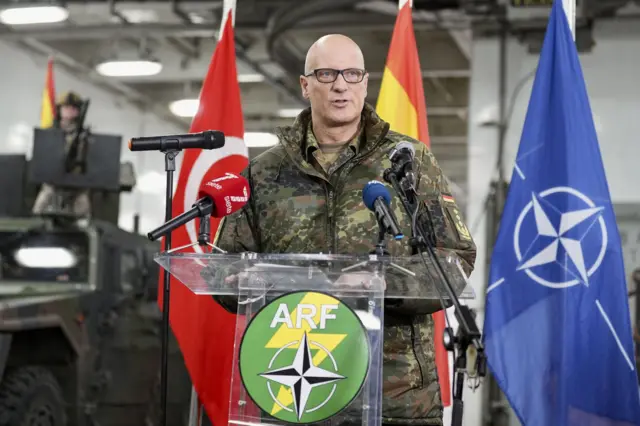 NATO Brunssum Müşterek Kuvvetler Komutanlığı Komutanı Alman General Ingo Gerhartz, STEADFAST DART 26 deniz tatbikatı hakkında bir konuşma yaparken. Arkada Türkiye, İspanya ve NATO bayrakları görülüyor. 