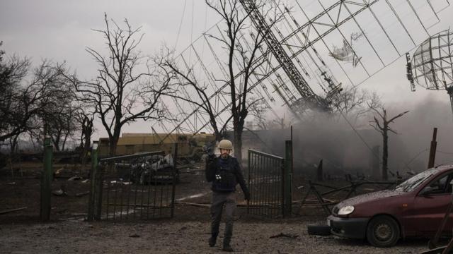 Фотограф Мстислав Чернов на фоне базы ПВО после российского удара в Мариуполе, 24 февраля 2022 года (фотография Евгения Малолетки)