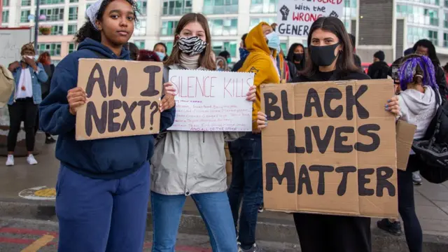 Trois manifestantes tiennent des affiches de Black Lives Matters