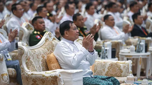  ပုဆိုးနဲ့တိုက်ပုံဝတ်ထားတဲ့ ဗိုလ်ချုပ်မှူးကြီးမင်းအောင်လှိုင်ကို နေပြည်တော်က အခမ်းအနားတစ်ခုမှာထိပ်ဆုံးမှာထိုင်နေတာကို တွေ့ရစဥ်၊ အခြားသူများရဲ့ထိုင်ခုံတွေထက် ပိုမိုကြီးမားသော ဆိုဖာကြီးတစ်ခုပေါ်တွင် ထိုင်နေခြင်းဖြစ်ပါတယ်။