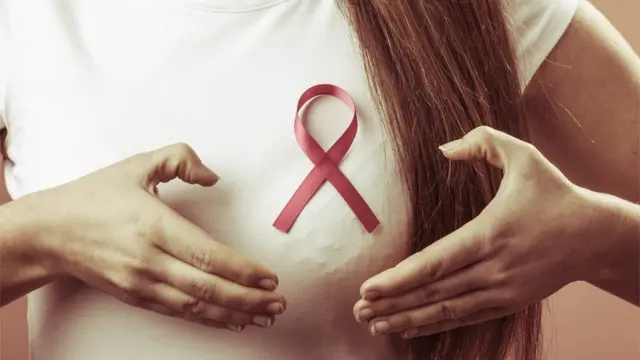 બ્રેસ્ટ કૅન્સર સામેની લડતની સાઇન સાથે મહિલાના બ્રેસ્ટની તસવીર