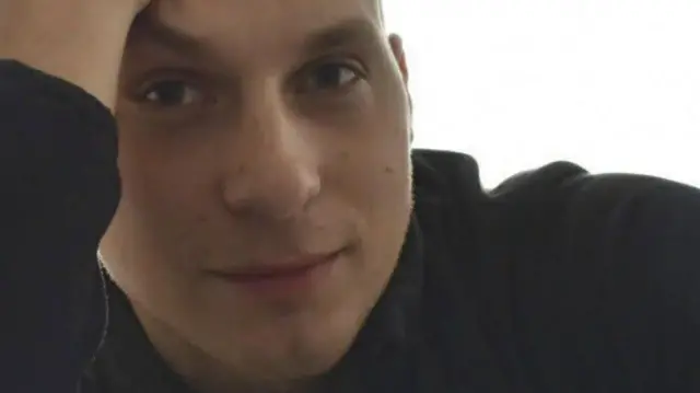 Мирославас Троцкис - молодой человек в темной одежде смотрит с улыбкой в камеру