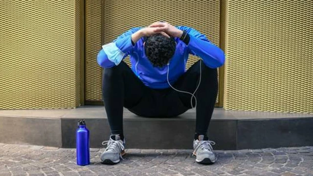 Homem com roupa esportiva sentado com as maos na cabeça