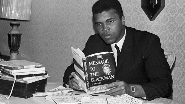 Former heavyweight boxing champion Muhammad Ali reading the book "Message to the Black Man."