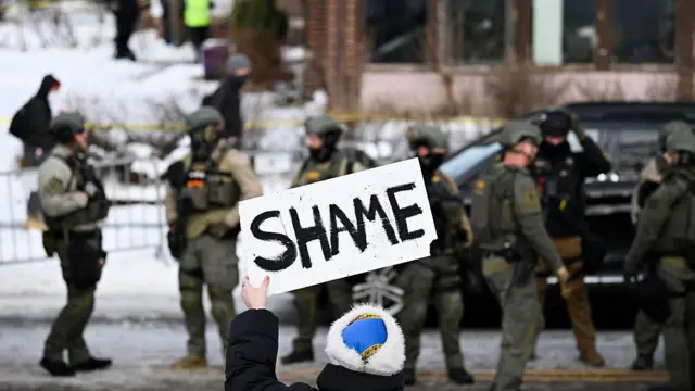 Halktan bir kişinin kolluk kuvvetleri mensuplarına "Utanın" yazılı bir pankart tuttuğu görülüyor