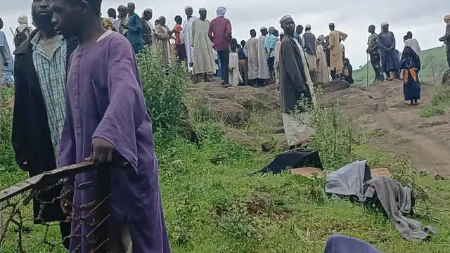 مجموعة من الأشخاص يقفون أعلى جبل، وحولهم بعض من متعلقات وملابس أشخاص.