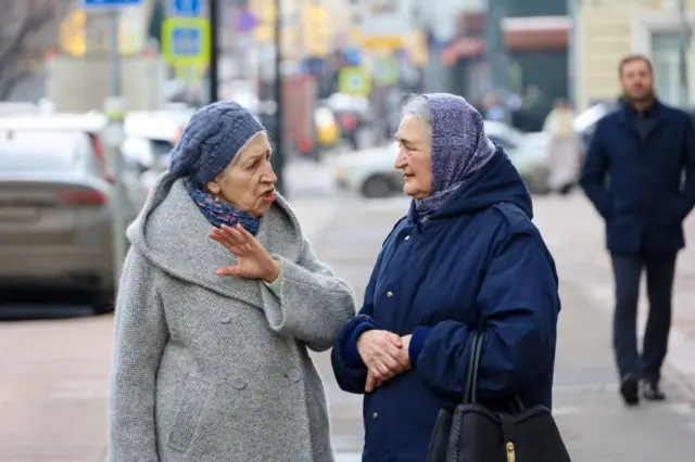 Две пожилые женщины разговаривают друг с другом на московской улице